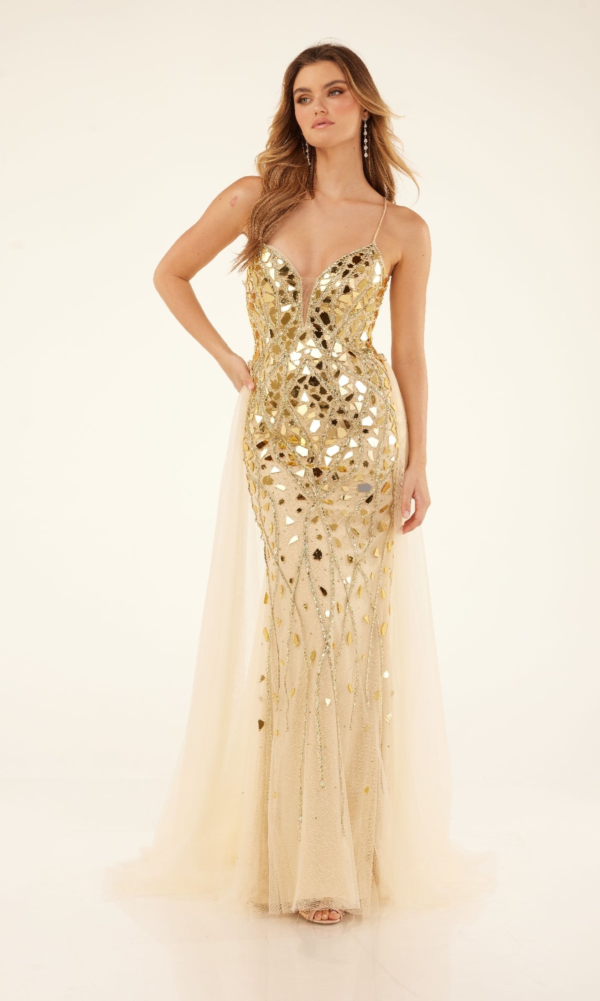 A woman in the Cecilia Couture C132 long prom dress—featuring gold sequins, a deep V neckline, lace-up back, and sheer panels—stands against a plain light background.